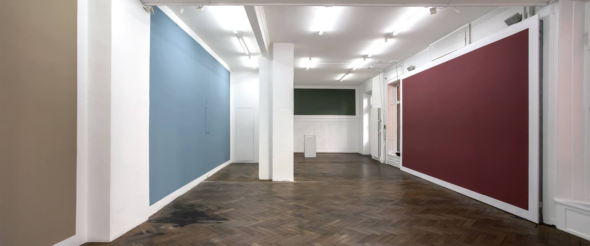 Gallery interior with large blue and deep red wall paintings